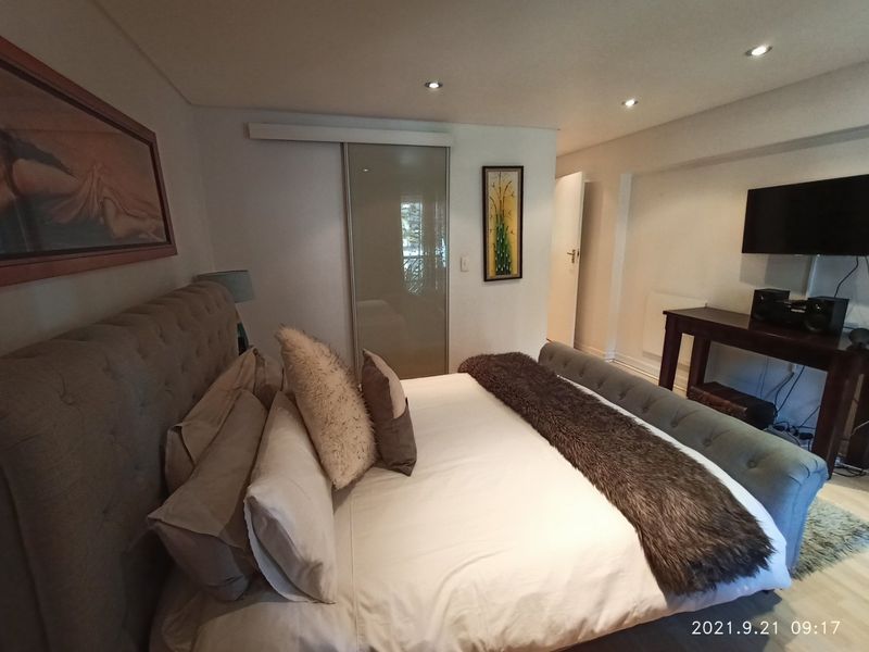 A well-maintained bedroom featuring recessed downlighting and a modern sliding glass door, providing a clean and functional living space.