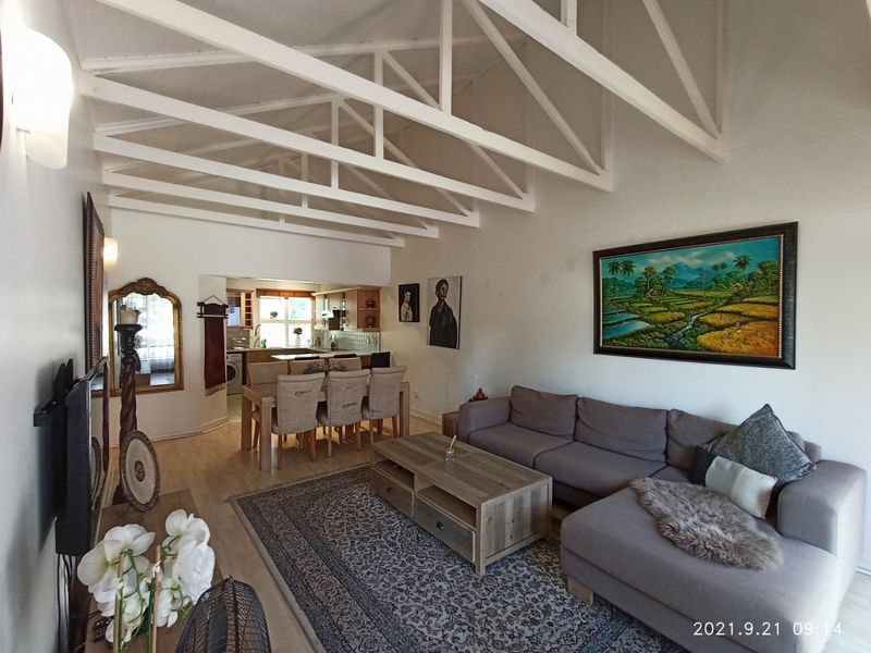 Spacious open-plan living and dining area featuring high vaulted ceilings with exposed white trusses and integrated kitchen space.