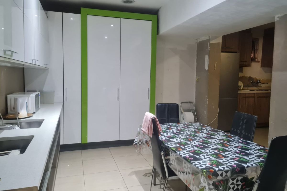 Kitchen area featuring modern white and green cabinetry, tiled flooring, and recessed lighting, currently requiring finishing touches to wall surfaces and surrounding areas.