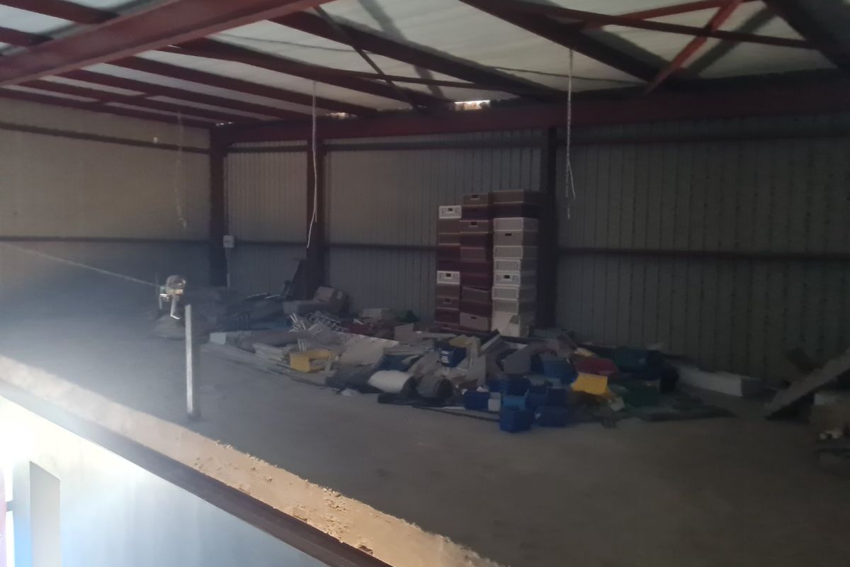 An open-plan mezzanine utility space featuring exposed steel structural beams and metal wall cladding, currently used for storage.