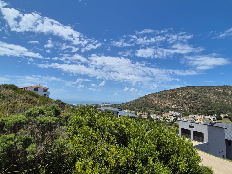 Elevated view overlooking the surrounding residential estate, coastal landscape, and hillside terrain, showcasing the scenic location of the vacant land.