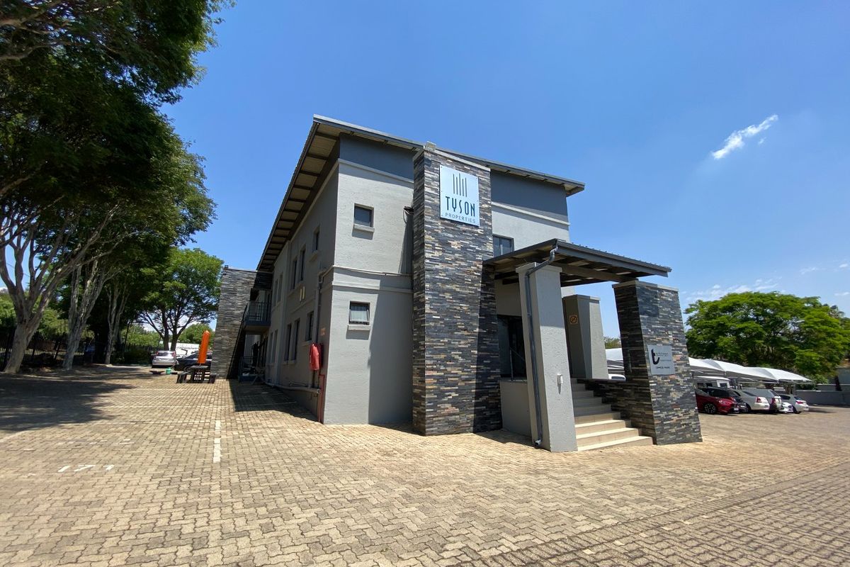 Front exterior view of a commercial building featuring stone cladding accents, a covered entrance with concrete stairs, and an adjacent paved parking area.