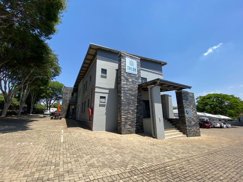 Front exterior view of a commercial building featuring stone cladding accents, a covered entrance with concrete stairs, and an adjacent paved parking area.