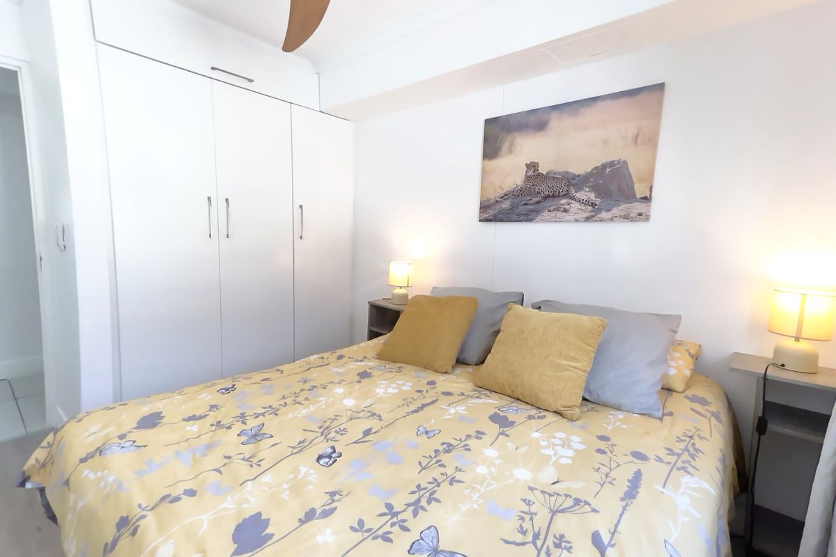 A well-maintained bedroom featuring built-in cupboards and a ceiling fan, offering a clean and functional living space.