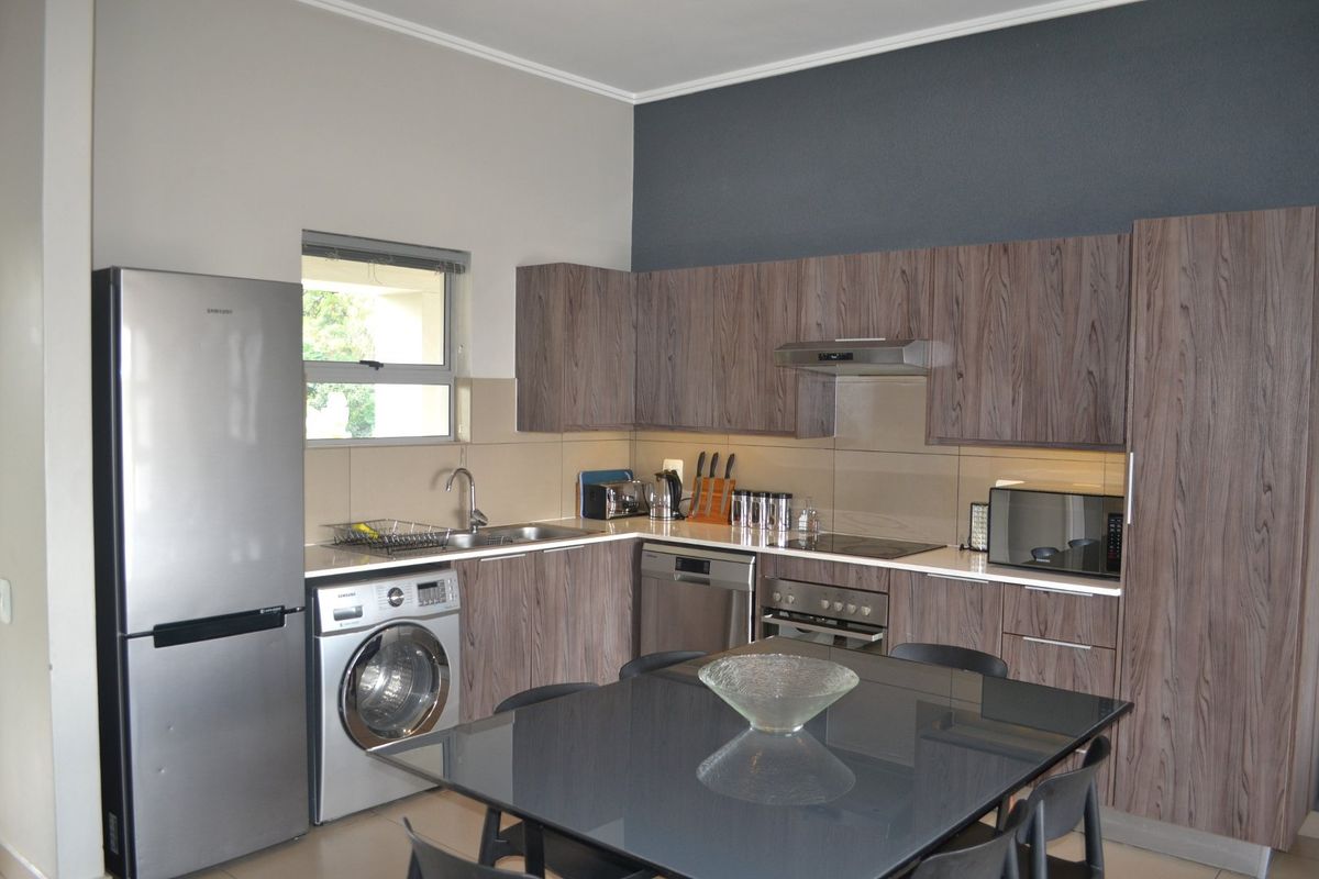 Modern kitchen featuring wood-grain cabinetry, integrated appliances, tiled backsplash, and functional layout with ample storage and workspace.