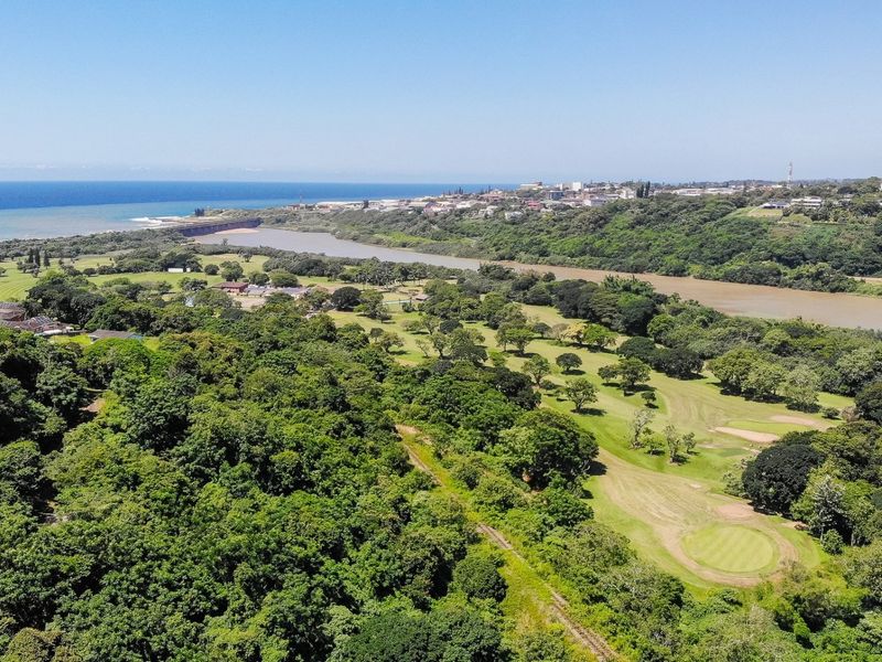 An expansive aerial view showcasing the surrounding landscape, including a golf course, river, and coastal scenery.