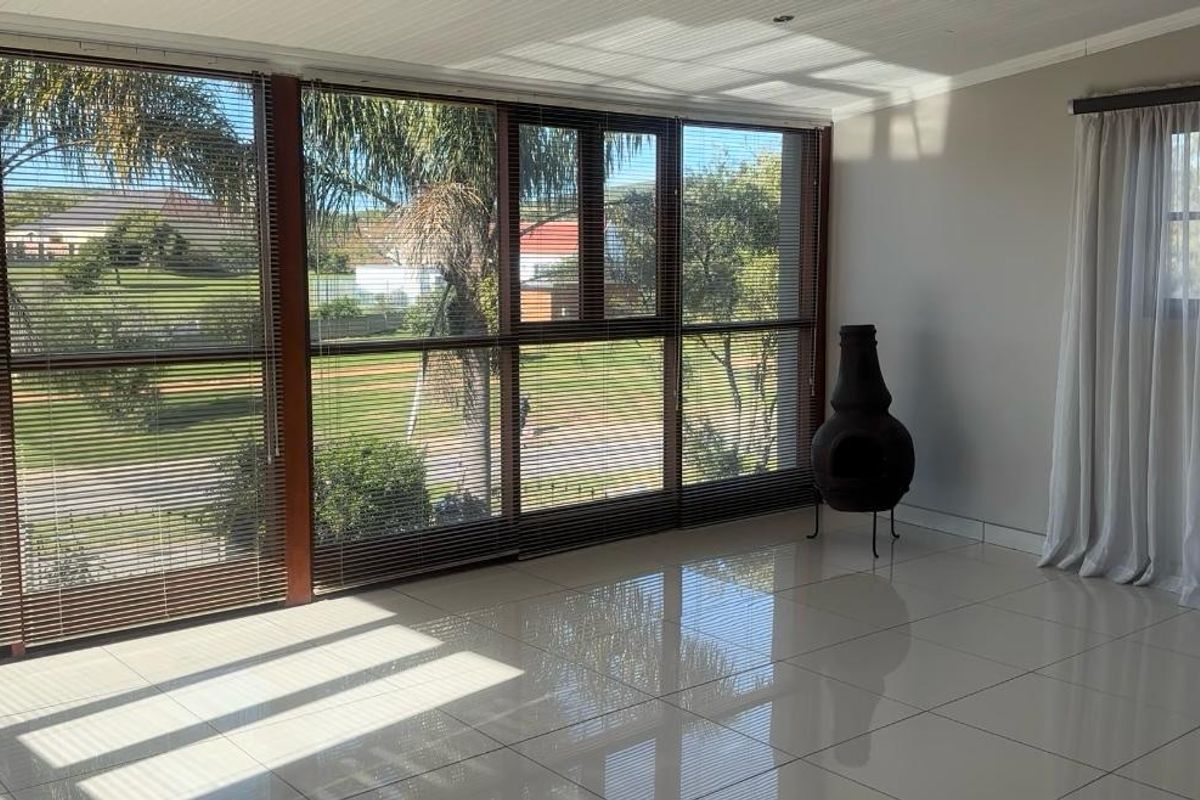 Bright and spacious living area featuring large floor-to-ceiling windows with integrated blinds, polished porcelain tile flooring, and a neutral color palette.