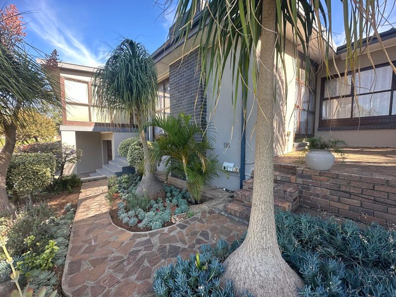A view of the property's exterior front facade featuring a stone-paved walkway, brick steps, and established garden landscaping.