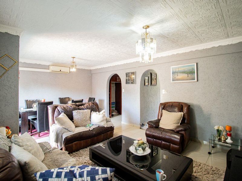 Open-plan living and dining area featuring textured ceilings, tiled flooring, and arched entryways, providing a functional and connected living space.