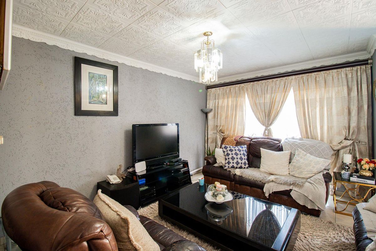 A living room featuring textured ceiling tiles, decorative cornice, and a crystal chandelier, providing a traditional aesthetic with textured wall finishes.