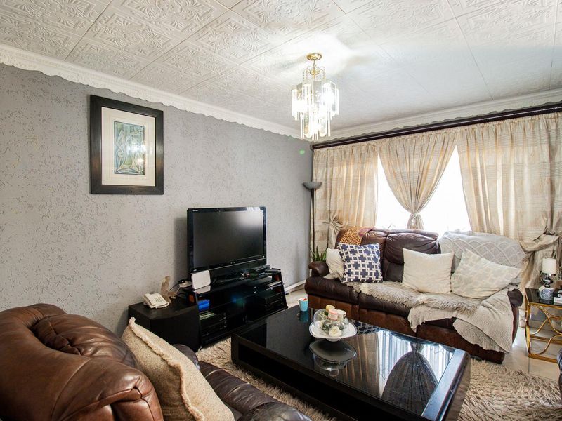 A living room featuring textured ceiling tiles, decorative cornice, and a crystal chandelier, providing a traditional aesthetic with textured wall finishes.