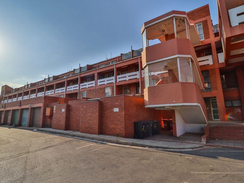 Exterior view of a multi-story apartment complex featuring brick facade, integrated garage units, and a prominent stairwell tower.