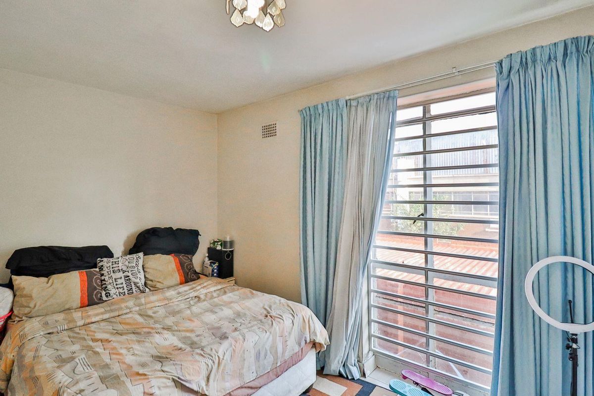 A standard bedroom featuring a large window with integrated security bars and a central ceiling light fixture.
