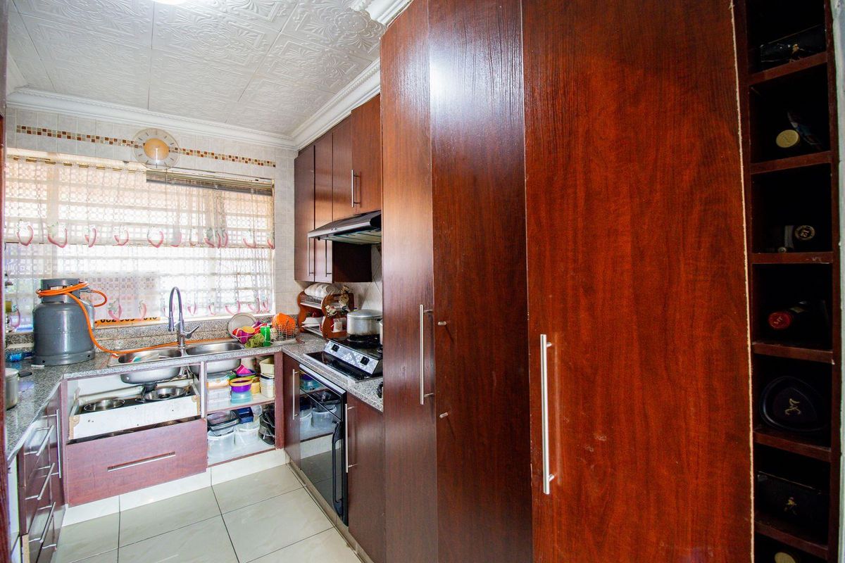 Compact kitchen featuring dark wood cabinetry, granite countertops, built-in oven, hob, extractor fan, and a dedicated wine storage rack.