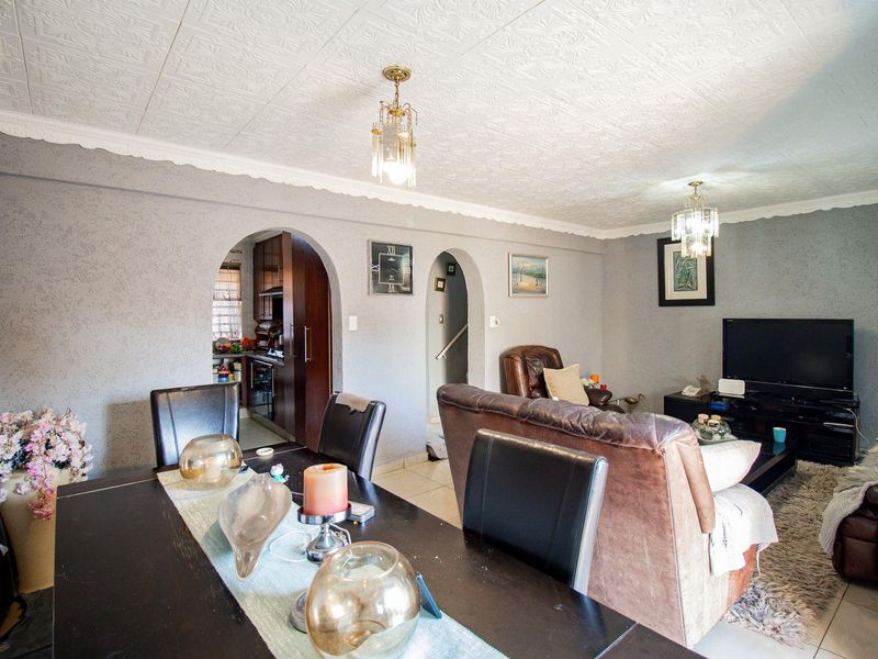 Open-plan living and dining area featuring arched doorways, textured ceilings, and tiled flooring, providing a functional layout with access to adjacent rooms.
