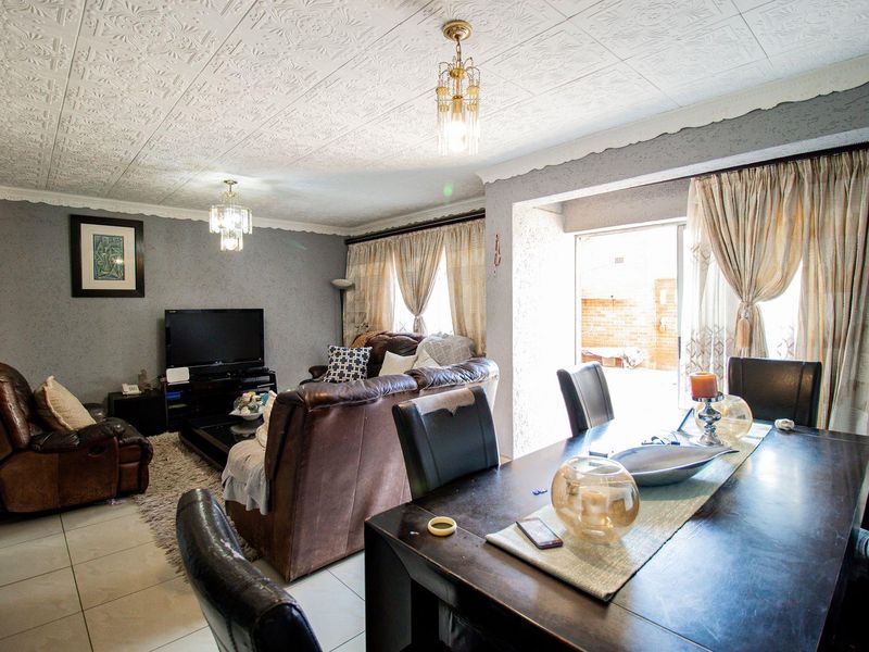 Open-plan living and dining area featuring tiled floors, decorative ceiling tiles, and sliding door access to the exterior.