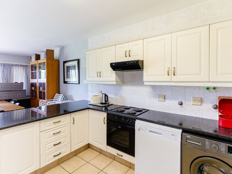 Open-plan kitchen featuring granite countertops, built-in cabinetry, and integrated appliances, seamlessly flowing into the adjacent living area.