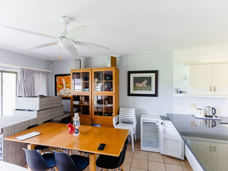 Open plan living and kitchen area featuring tiled flooring, granite countertops, built-in cabinetry, and a ceiling fan with access to a sliding glass door.