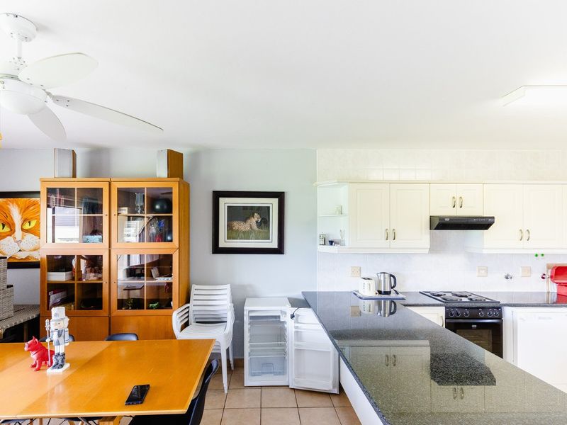 Open-plan kitchen and dining area featuring granite countertops, built-in cabinetry, and a ceiling fan, providing a functional space for cooking and dining.