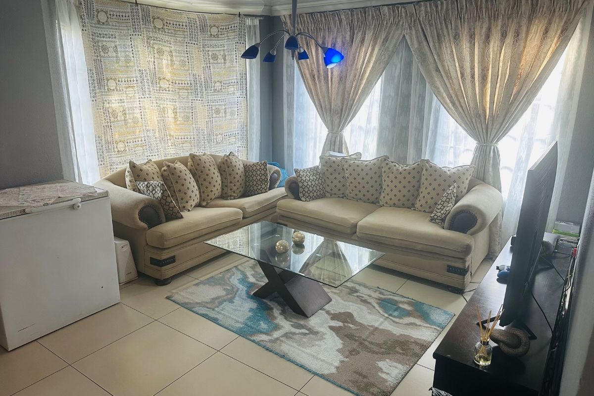 A comfortable living room featuring tiled flooring and a central ceiling light fixture, providing a functional space for relaxation.