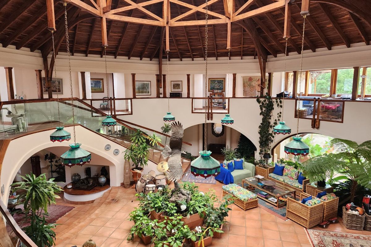 Spacious open-plan living area featuring a dramatic vaulted timber ceiling, terracotta flooring, and a mezzanine level with glass balustrades.