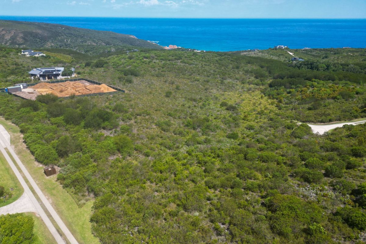 An aerial view of a vacant residential plot featuring natural coastal vegetation and proximity to the ocean.