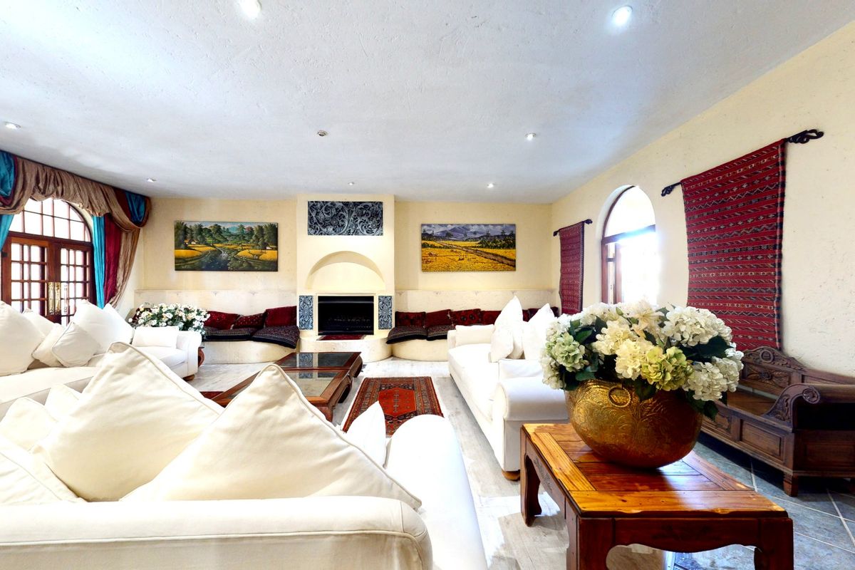 Spacious living room featuring a central built-in fireplace, arched windows, and tiled flooring, offering a warm and inviting atmosphere.