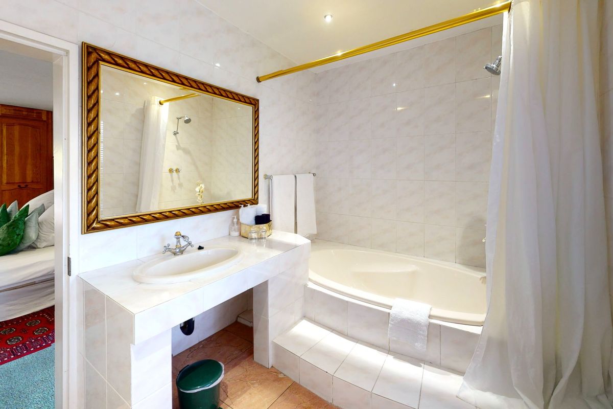 A functional bathroom featuring a built-in bathtub with shower, tiled vanity with integrated sink, and a large wall-mounted mirror.