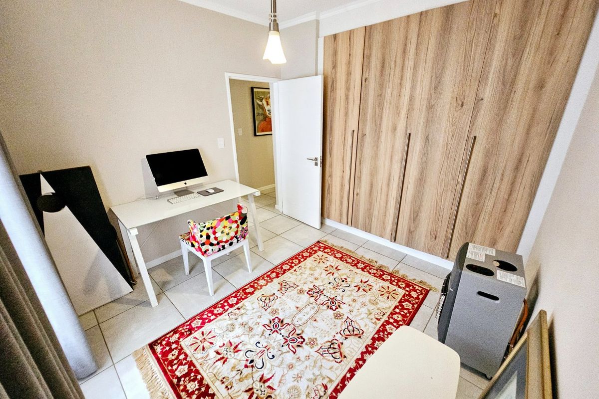 A bedroom featuring light wood-finish built-in cupboards and neutral tiled flooring, offering a functional space with ample storage.