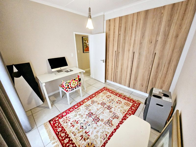 A bedroom featuring light wood-finish built-in cupboards and neutral tiled flooring, offering a functional space with ample storage.