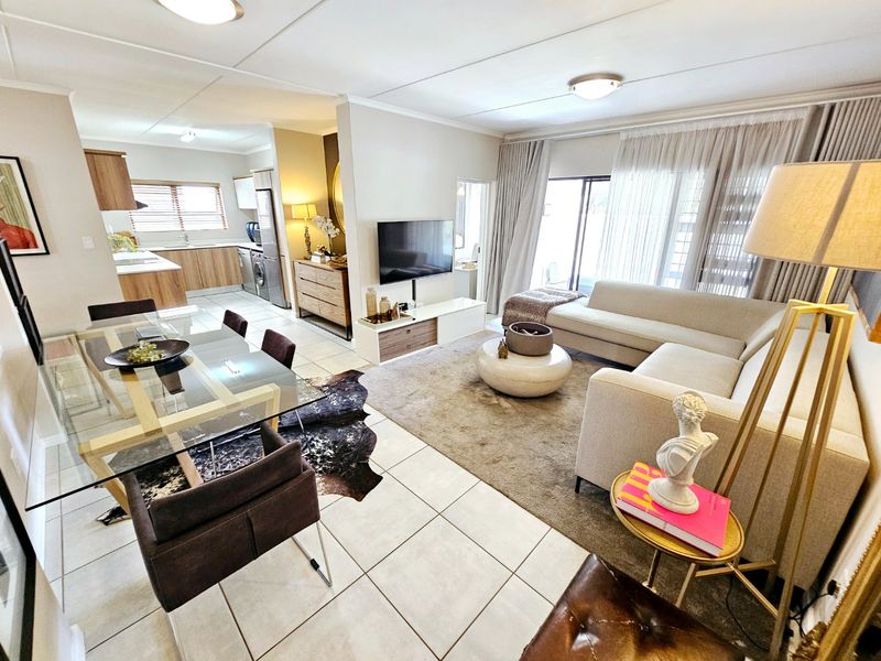 Spacious open-plan living and dining area featuring tiled floors, modern kitchen cabinetry, and large sliding doors leading to an outdoor space.