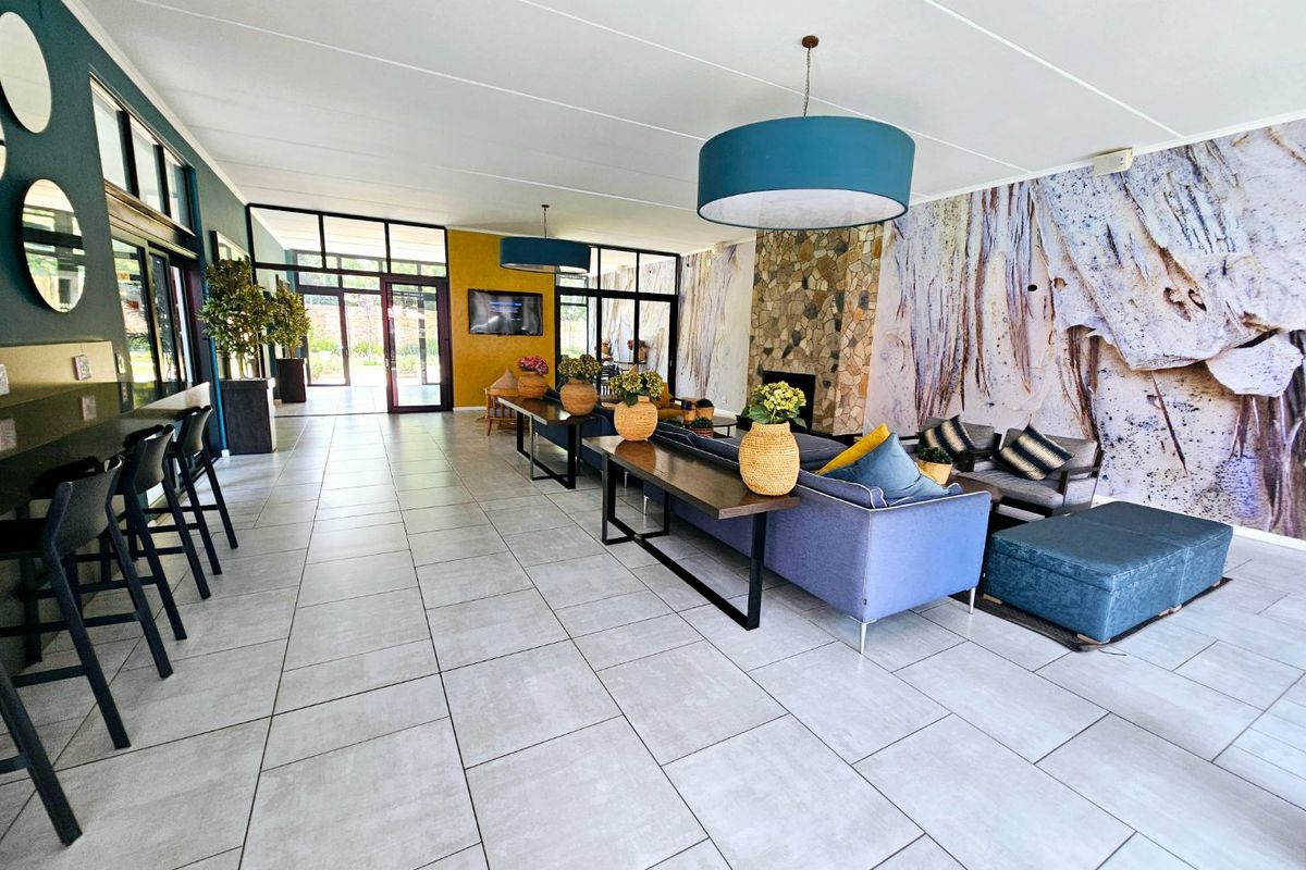 Spacious open-plan living area featuring large format floor tiles, a stone fireplace, and extensive glass doors providing ample natural light.