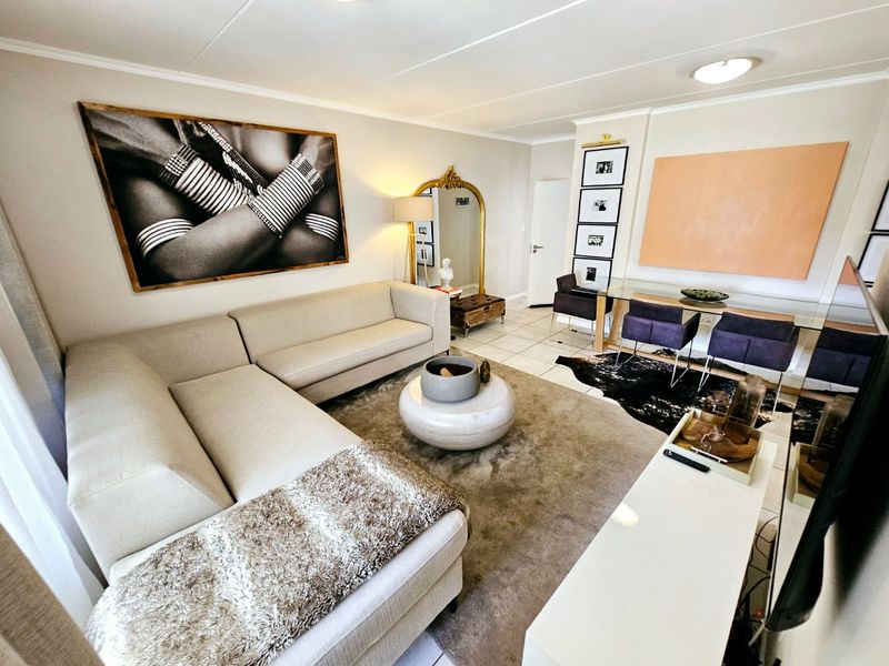 A well-maintained open-plan living and dining area featuring neutral tiled flooring and recessed ceiling lighting, creating a bright and cohesive living space.