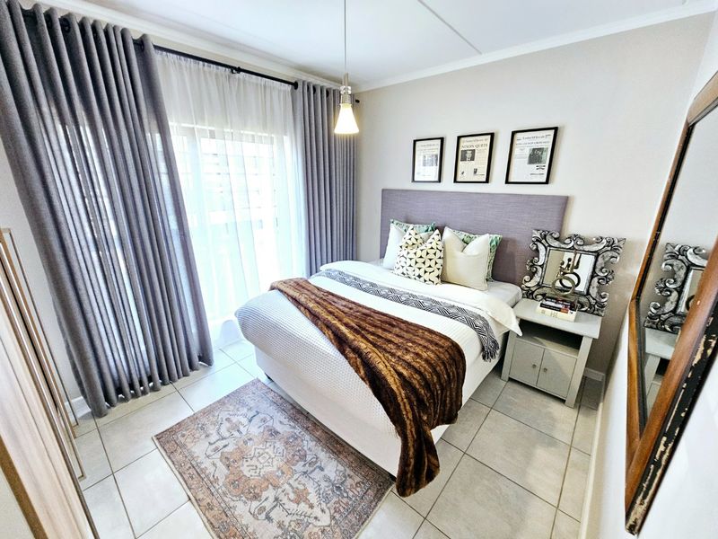 A well-maintained bedroom featuring tiled flooring, a built-in headboard, and a sliding glass door providing access to an outdoor area.