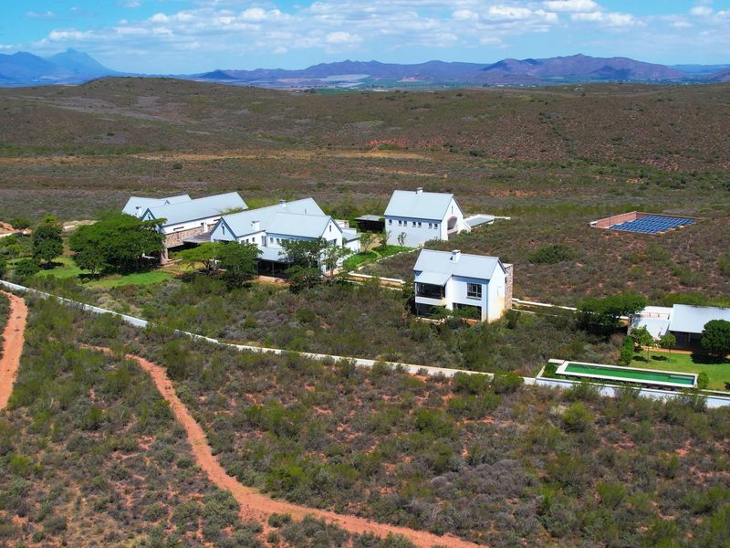 Aerial view of a sprawling farm estate featuring multiple buildings, a swimming pool, and a solar panel array set within a vast landscape.