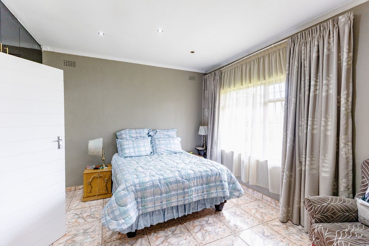 A well-lit bedroom featuring tiled flooring, recessed downlighting, and large windows with curtain tracks, offering a neutral base for personalization.