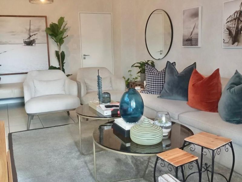 A well-maintained living room featuring neutral tiled flooring, modern pendant lighting, and a clean, bright interior finish.