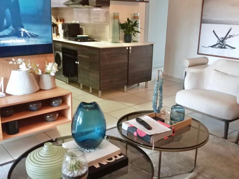 An open-plan living area featuring a modern kitchen with built-in cabinetry, gas hob, and integrated oven, seamlessly connected to the lounge space.