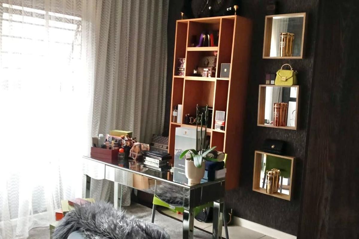 A bedroom featuring dark textured wallpaper, wall-mounted shelving units, decorative mirrors, and a modern ceiling light fixture.