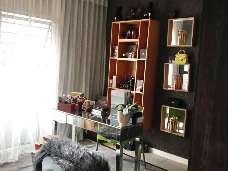 A bedroom featuring dark textured wallpaper, wall-mounted shelving units, decorative mirrors, and a modern ceiling light fixture.