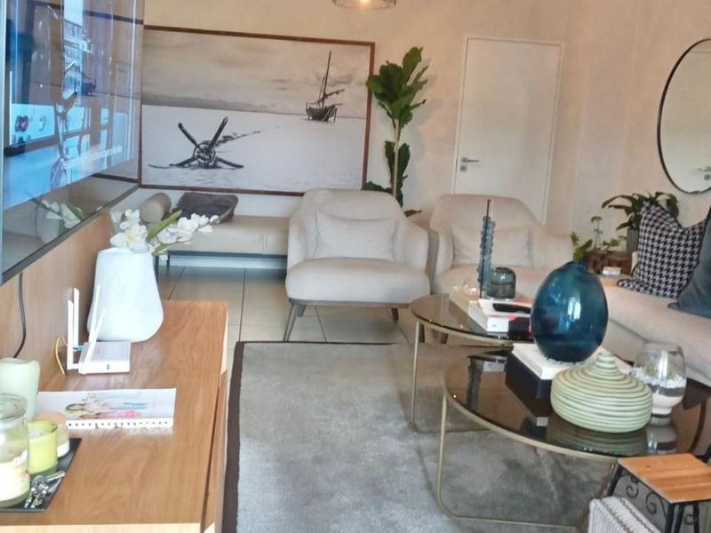 A well-maintained living room featuring tiled flooring, modern pendant lighting, and a neutral color palette, creating a comfortable and inviting atmosphere.