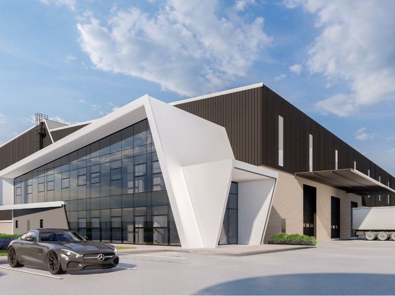 Modern industrial facility featuring a striking glass facade, metal cladding, and dedicated loading bays with a spacious concrete apron for logistics operations.