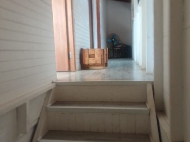 A narrow hallway featuring timber wall paneling and a timber ceiling, leading up a small set of stairs to an adjacent living area.