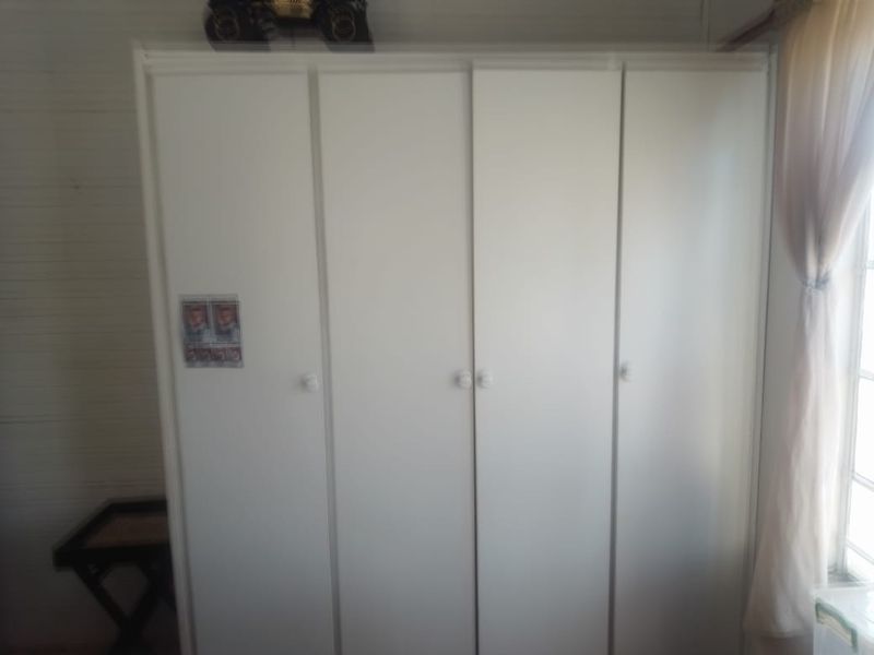 A bedroom featuring a white built-in wardrobe with multiple doors.