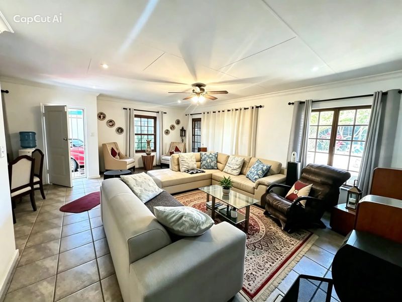 Spacious living room featuring tiled flooring, a ceiling fan, and large windows that provide ample natural light.