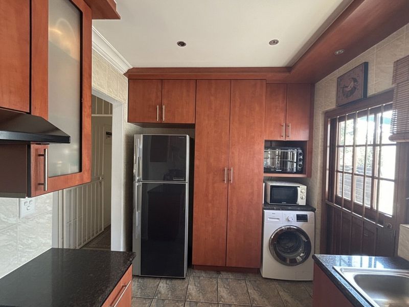 A functional kitchen featuring wood-finish cabinetry, granite countertops, tiled flooring, and integrated appliance spaces, offering a practical layout for daily meal preparation.