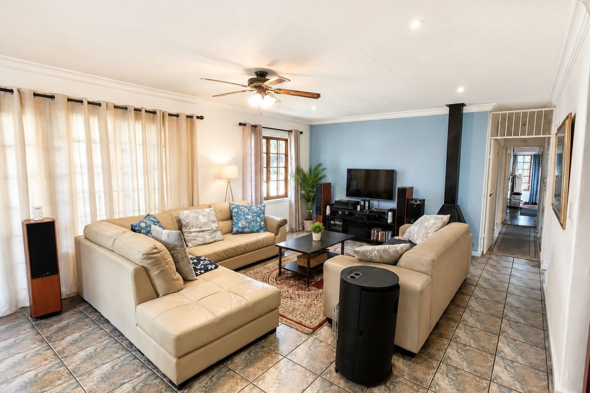 A spacious living room featuring tiled flooring, a ceiling fan, and a modern freestanding fireplace, creating a comfortable and functional family area.