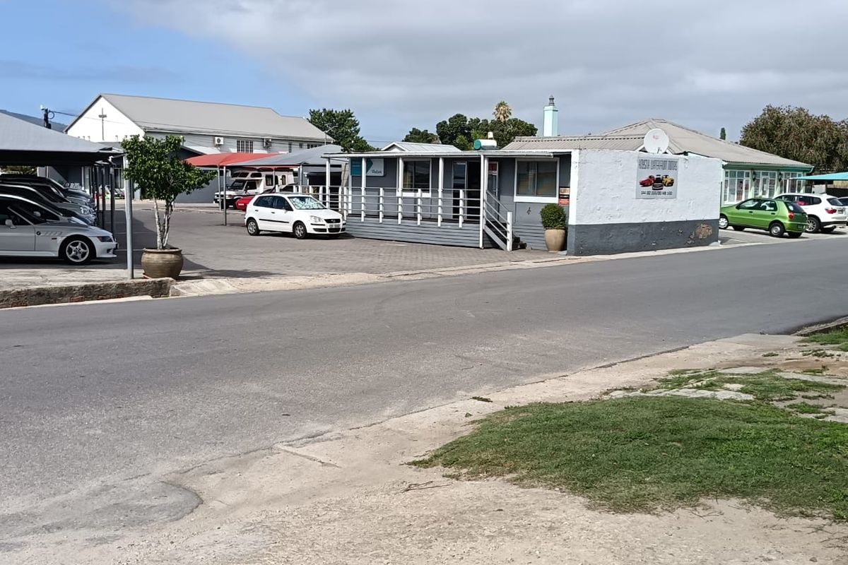Commercial property featuring a paved parking lot, covered parking bays, and a raised office structure with a timber deck entrance.