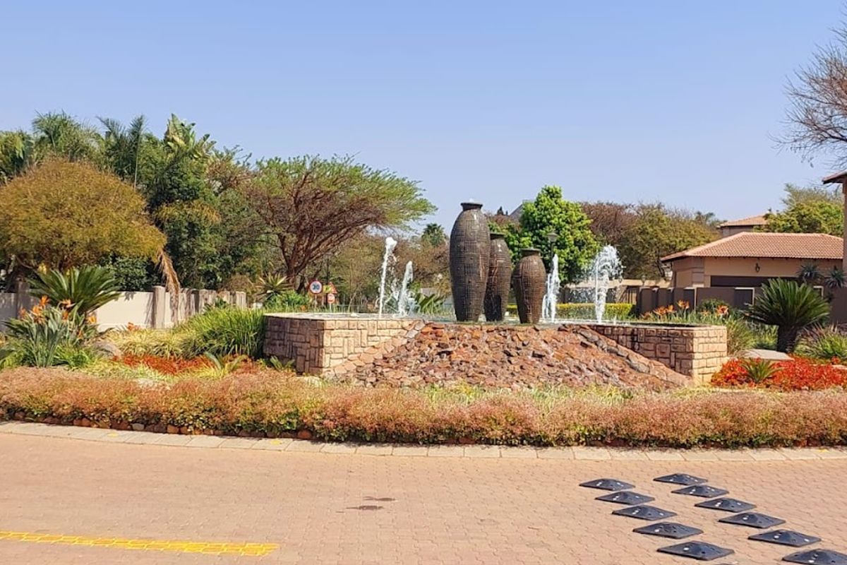A well-maintained landscaped garden feature with a central water fountain and stone-clad base located within a residential estate.