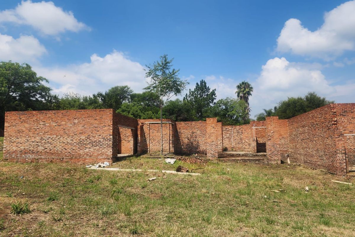 An unfinished residential building structure featuring exposed brick walls on a vacant plot, offering a blank canvas for development.